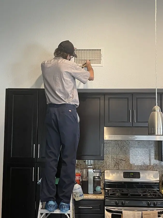 Technician inspecting an air vent during HVAC service in Chili